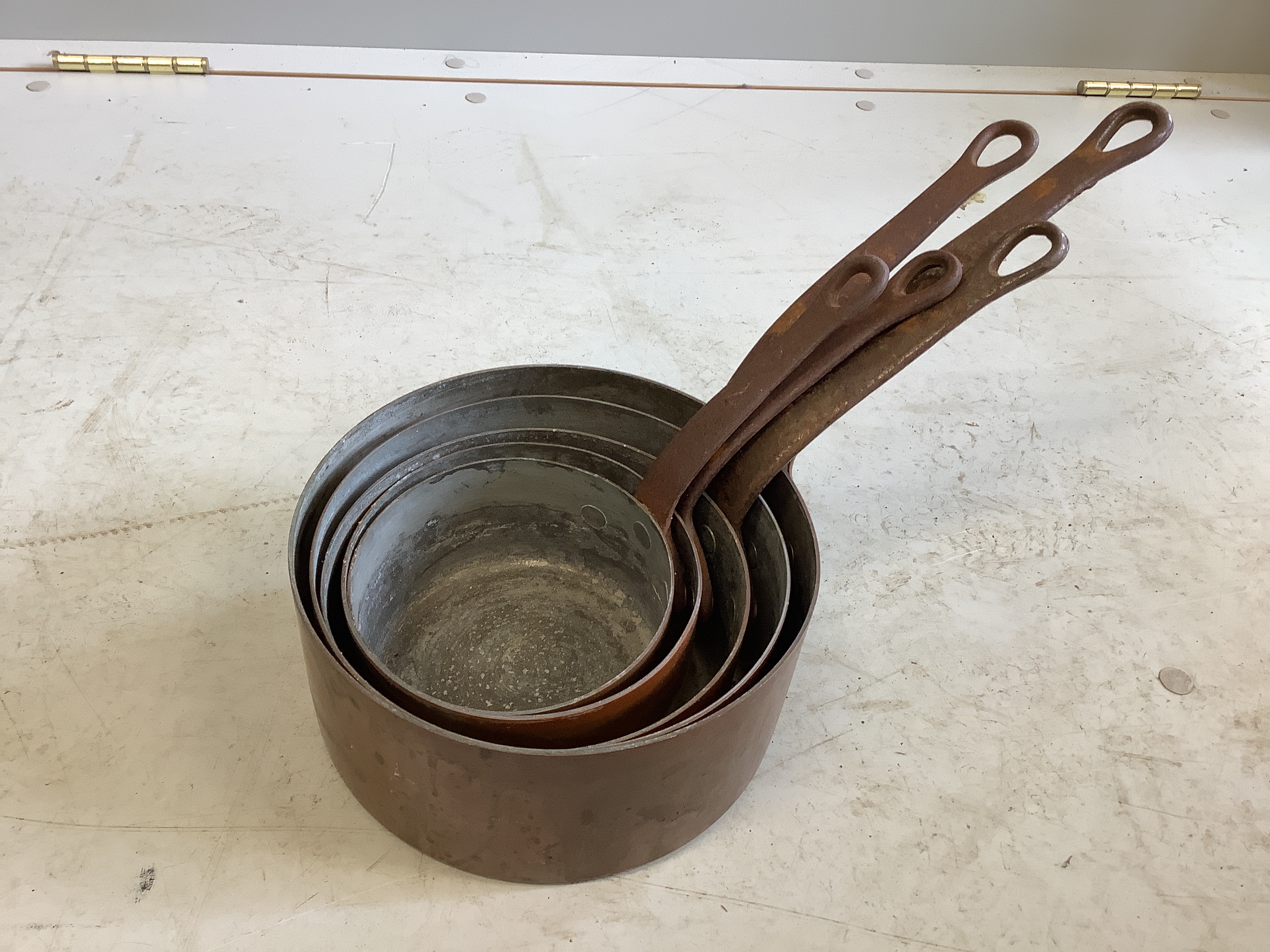 A graduated set of five circular copper saucepans, largest diameter 20cm